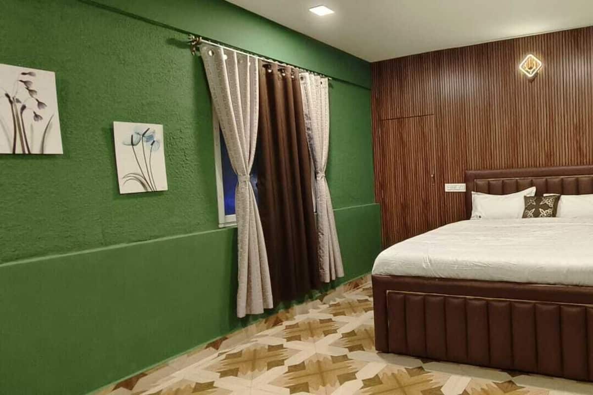 A bedroom with a wooden headboard, a patterned floor, and green walls.