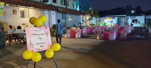 An outdoor event with tables set up for a ceremony, a banner, and balloons. - HIMALAYA POOL & RESORT (Tirupati)