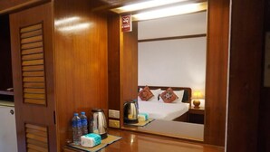 Una camera d'albergo con una scrivania in legno, uno specchio, un letto con cuscini, un comodino con una lampada e un cartello che indica il divieto di fumare.
