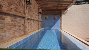 Una piscina con piastrelle blu, circondata da muri in mattoni e un soffitto in legno.