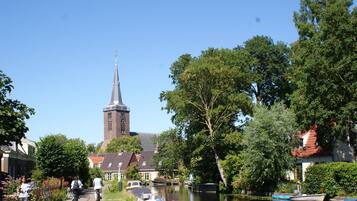 Een gracht met boten, een kerk met een hoge toren en een voetpad.