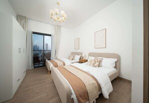 A hotel room with two beds, a balcony with a city view, and a chandelier. - Beachfront Apartment W Pool & Balcony Cyan Beach (Sharjah)