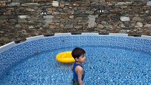 Ein Kind im Schwimmbecken, im Hintergrund eine Steinmauer.