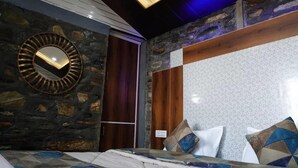 Ein Schlafzimmer mit einem großen Bett, einer Steinwand, einer Holzpaneelwand und einer Decke mit eingelassener Beleuchtung.