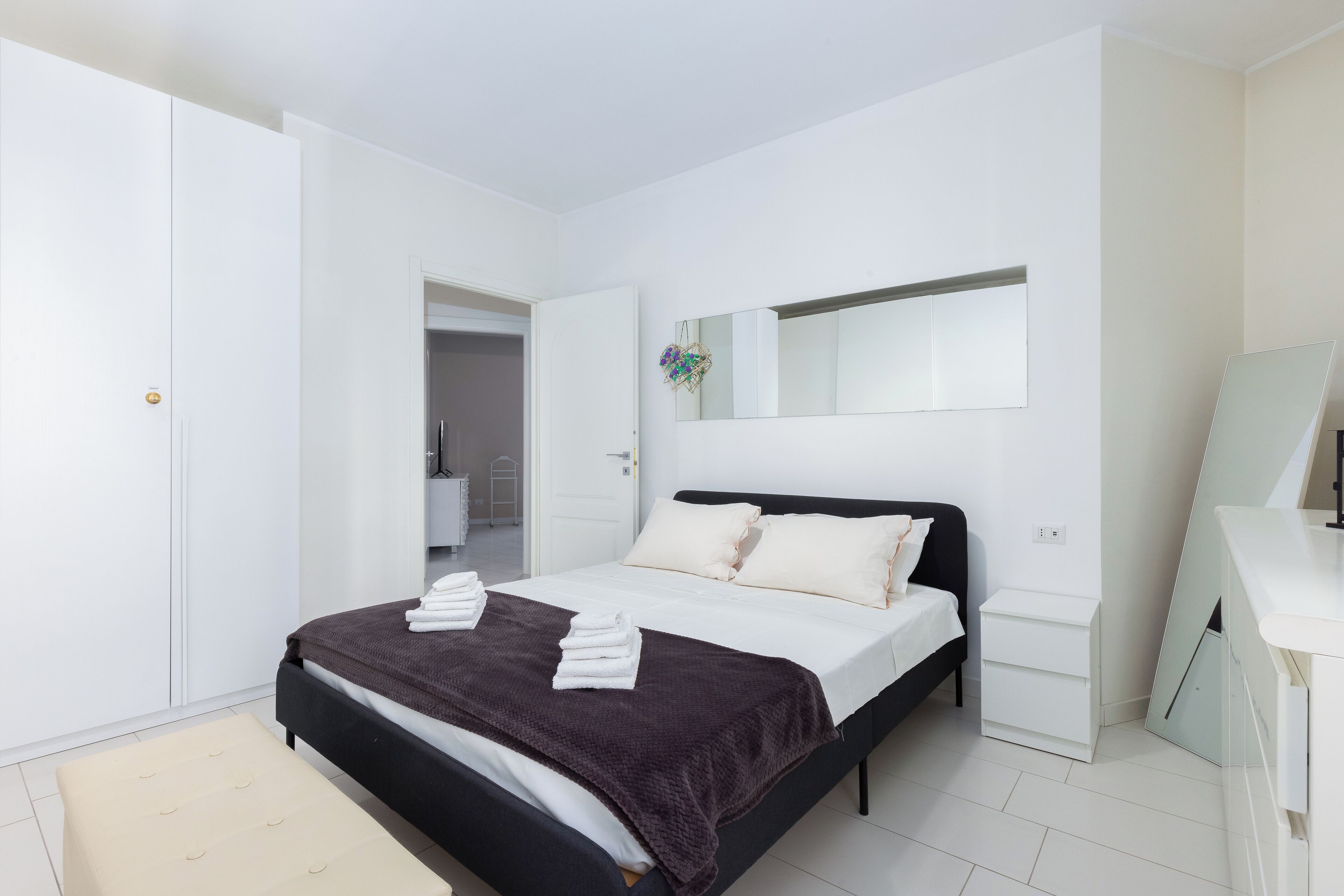 Ein modernes Schlafzimmer mit Bett, Nachttisch, Spiegel und Kleiderschrank.