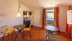 Un espacio habitable compacto con kitchenette, dos mesas de comedor y sillas.