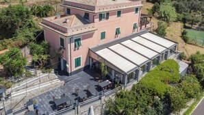 Un edificio de dos pisos con techo plano y un patio cubierto con mobiliario exterior.