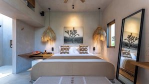Quarto moderno com cama grande, duas luminárias pendentes, pintura de uma árvore e um espelho refletindo a cama.