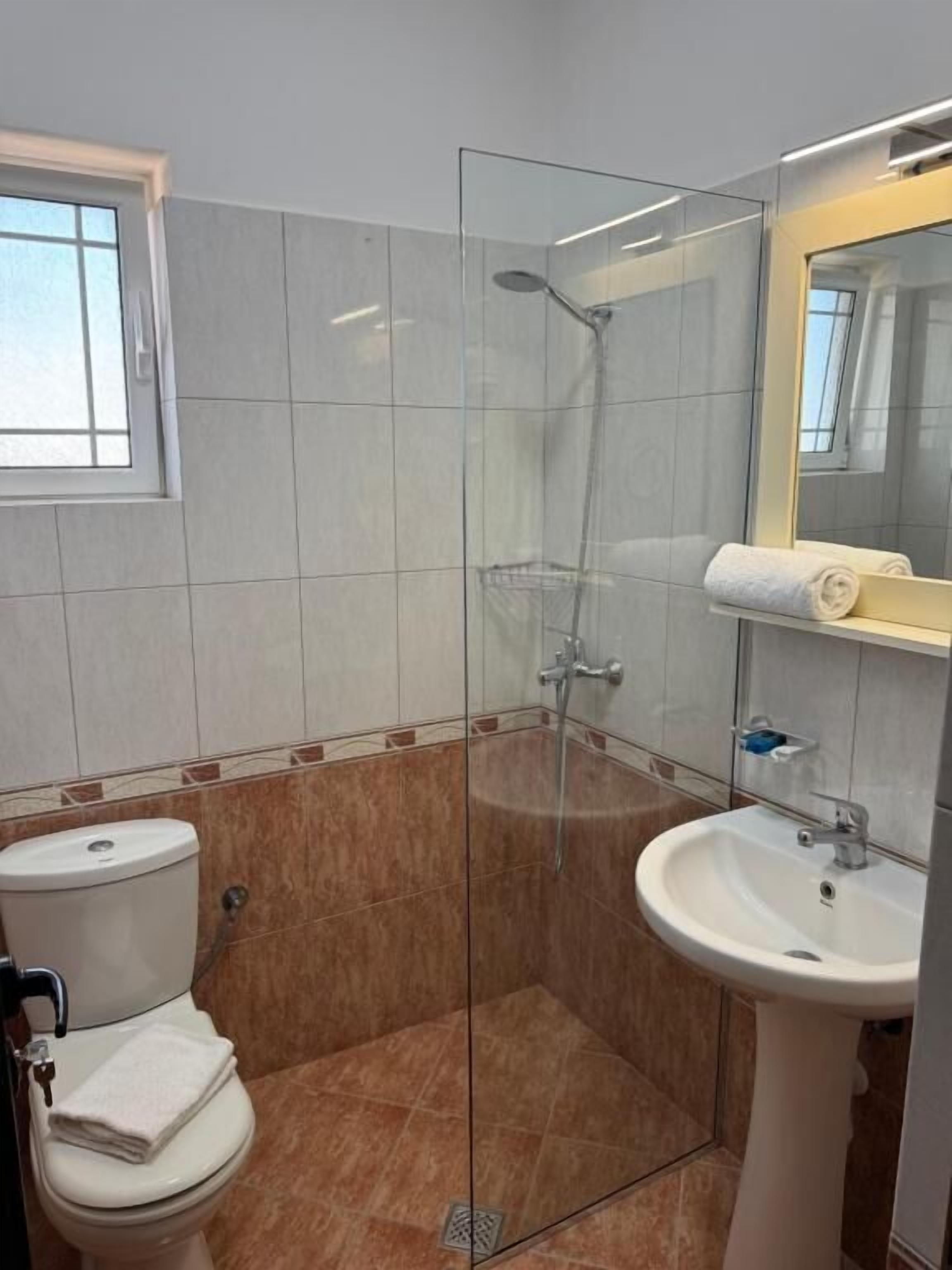 A bathroom with a glass-enclosed shower, a toilet, and a sink.