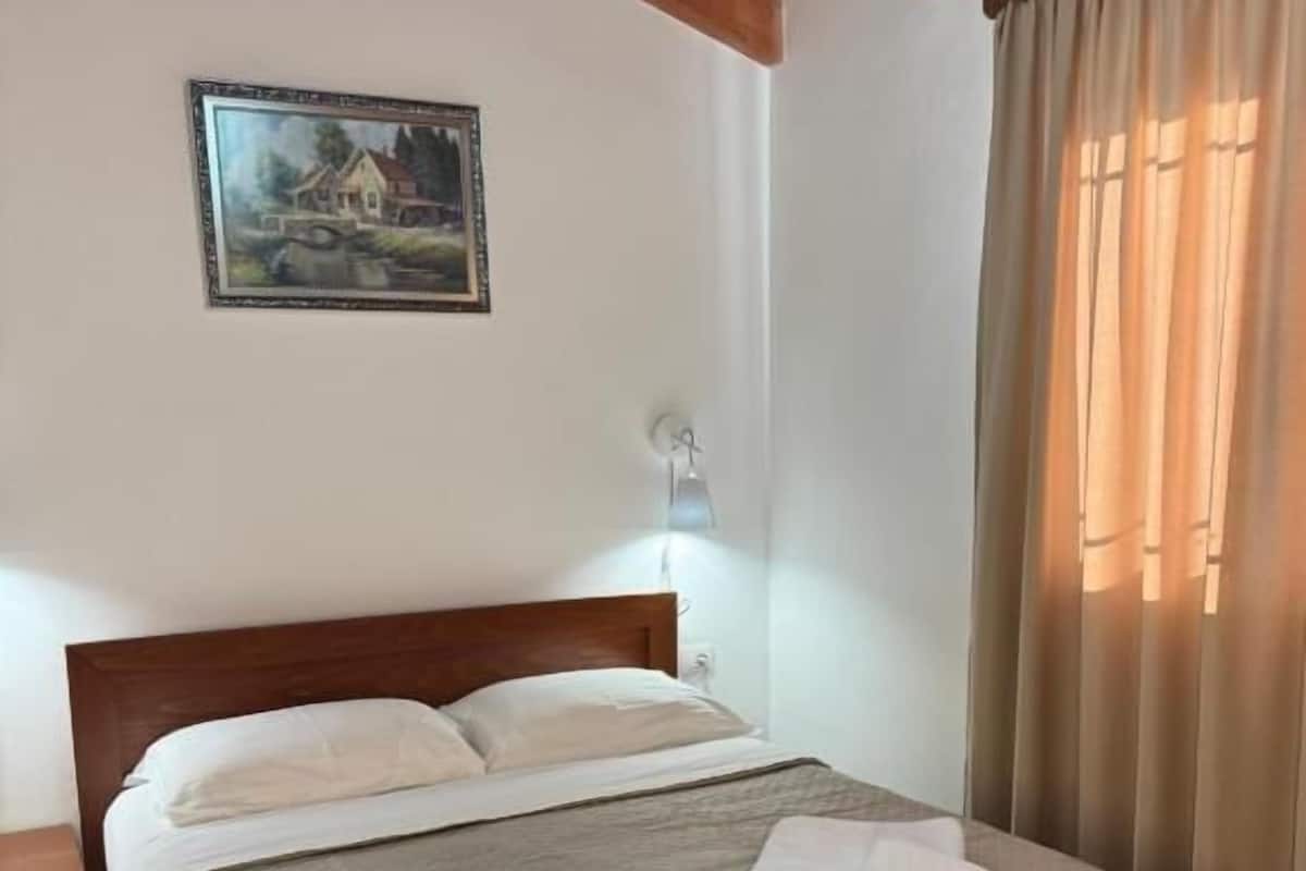 A neatly made bed with a wooden headboard, a bedside table, and a wall-mounted lamp.