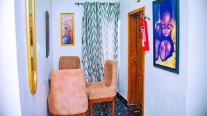 Un pasillo con dos sillones cómodos, una cortina estampada, un cuadro enmarcado y un extintor.