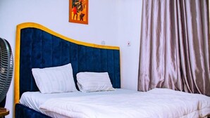Una cama con cabecera azul, ropa de cama blanca y una sola almohada.