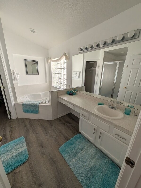 A bathroom with a bathtub, a sink, a vanity with a mirror, and a window. - LKB4705AW 4 Bedroom villa in Lake Berkley 4 Home (Kissimmee)