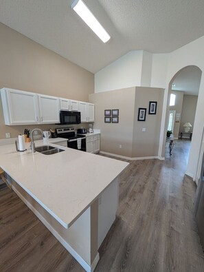 A kitchen with white cabinetry, a large island, and a microwave. - LKB4705AW 4 Bedroom villa in Lake Berkley 4 Home (Kissimmee)
