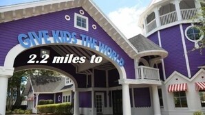 A purple building with a sign that reads "GIVE KIDS THE WORLD" and "2.2 miles to". - LKB4705AW 4 Bedroom villa in Lake Berkley 4 Home (Kissimmee)
