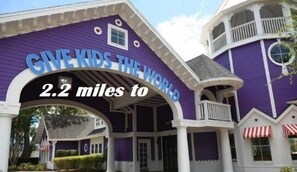 Un edificio morado con un letrero que dice "GIVE KIDS THE WORLD" y "2.2 millas".