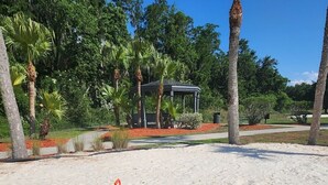 A sandy beach with a gazebo, palm trees, and a playground area. - LKB4705AW 4 Bedroom villa in Lake Berkley 4 Home (Kissimmee)