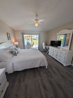 A bedroom with a bed, a dresser, a television, and a ceiling fan. - LKB4705AW 4 Bedroom villa in Lake Berkley 4 Home (Kissimmee)