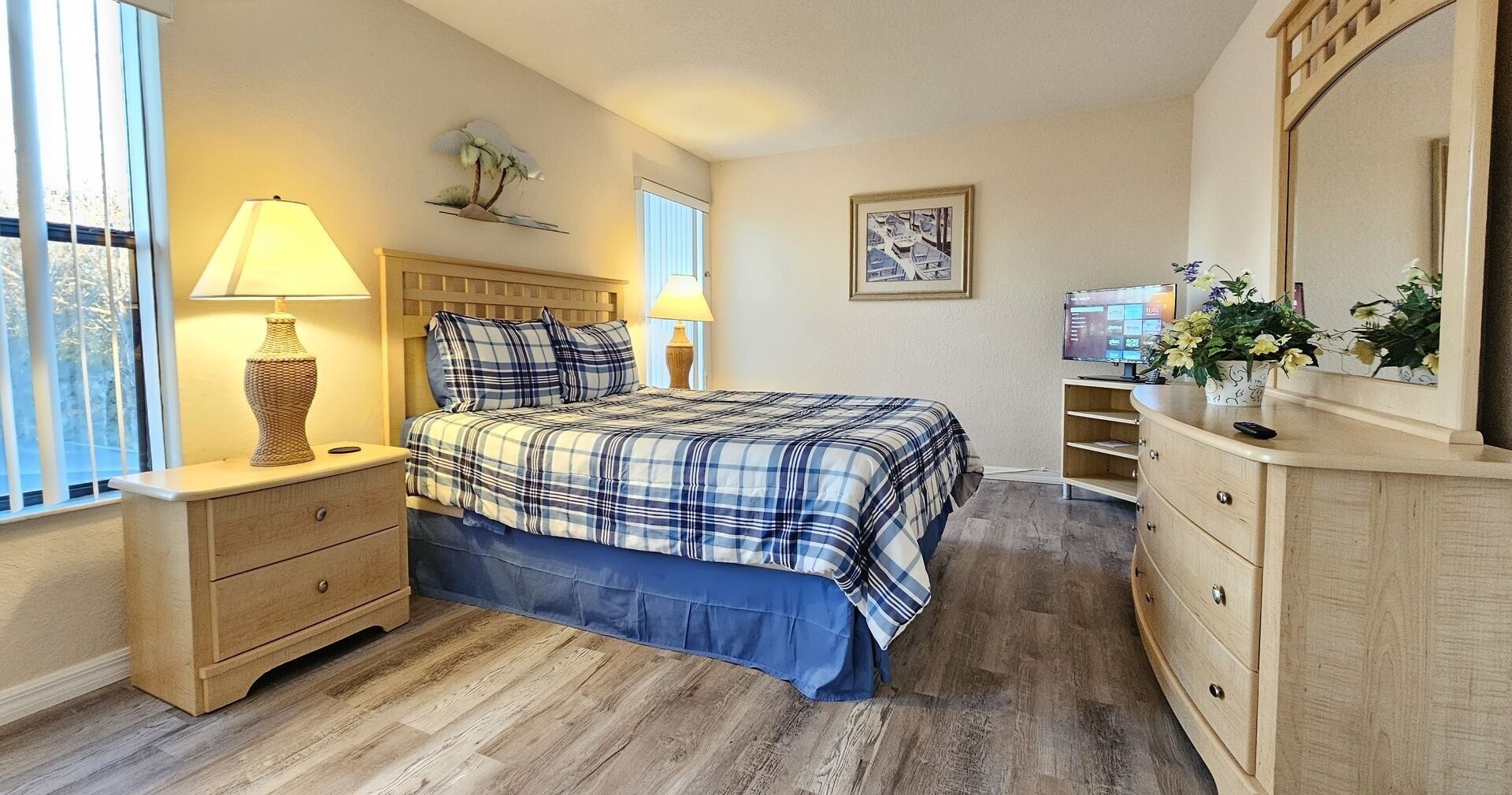 A bedroom with a bed, nightstands, a dresser, a mirror, and a window with blinds.