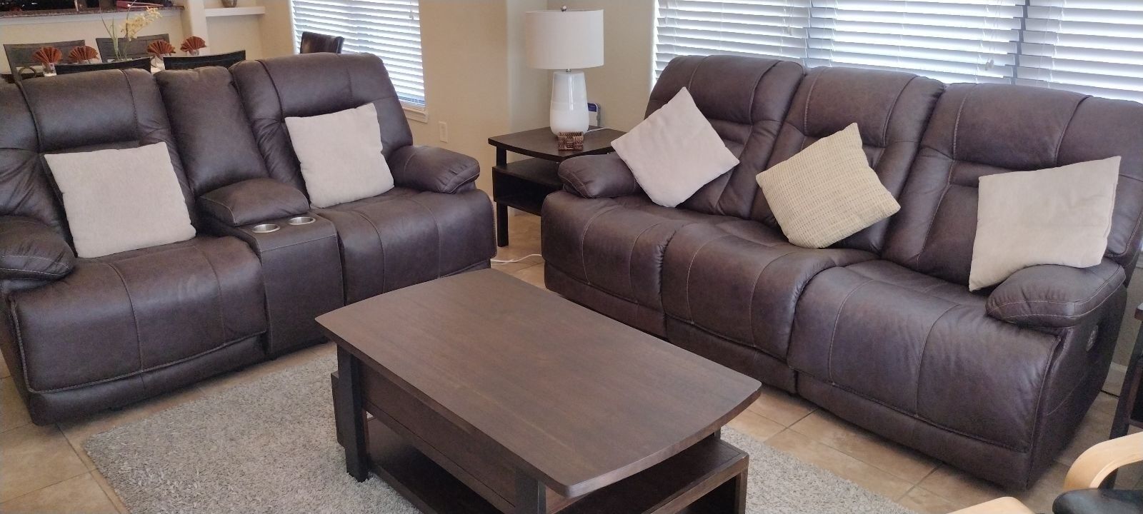 A living room with two brown leather sofas, a wooden coffee table, and a lamp on a side table.