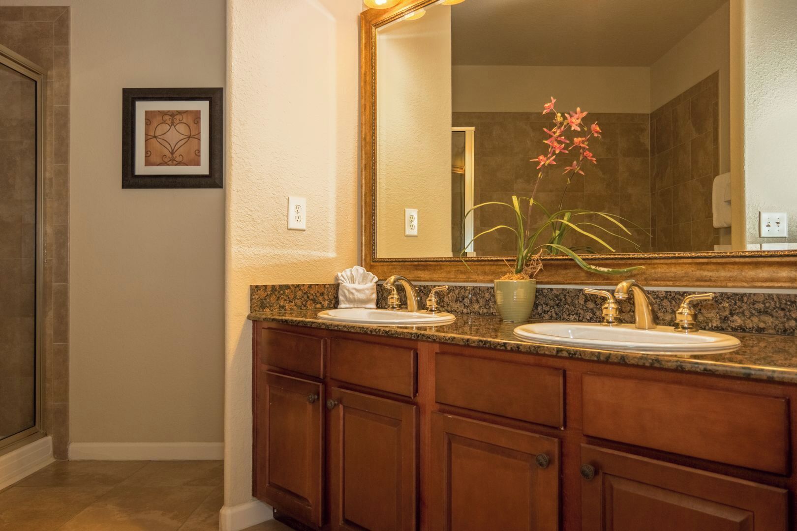 A bathroom with a double sink vanity, a large mirror, and a potted plant.