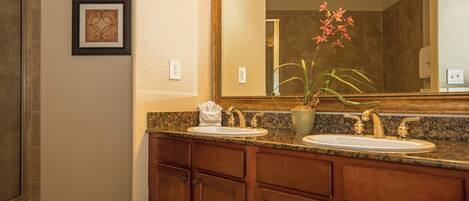 A bathroom with a double sink vanity, a large mirror, and a potted plant.