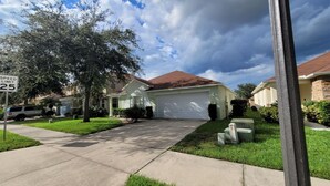 A suburban neighborhood with single-family homes, a speed limit sign of 25 mph, and a clear sky. - BT652RB 4 Bedroom Villa in Bella Toscana 4 Home (Davenport)