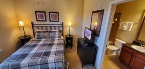 A bedroom with a bed, bedside lamps, a TV, and a bathroom with a sink and toilet. - BP835CP 4 Bedroom Condo in Bella Piazza 4 Condo (Davenport)