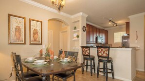 A dining area with a dark wooden table, black chairs, and framed artwork on the wall. - BP835CP 4 Bedroom Condo in Bella Piazza 4 Condo (Davenport)