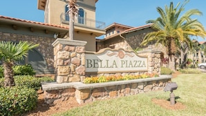 A stone sign with "Bella Pizzeria" written on it, surrounded by greenery and palm trees. - Bp726cp 3 Bed Bella Piazza Condo 3 Bedroom Condo (Davenport)