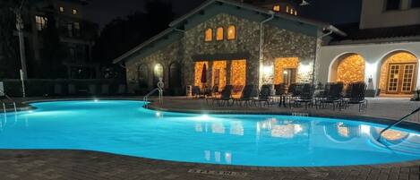 A swimming pool with lounge chairs and a stone building with arched windows.