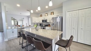 A modern kitchen with granite countertops, stainless steel appliances, and bar stools. - Sol1520sc 6 Bed Solana Holiday Villa 6 Bedroom Home (Davenport)