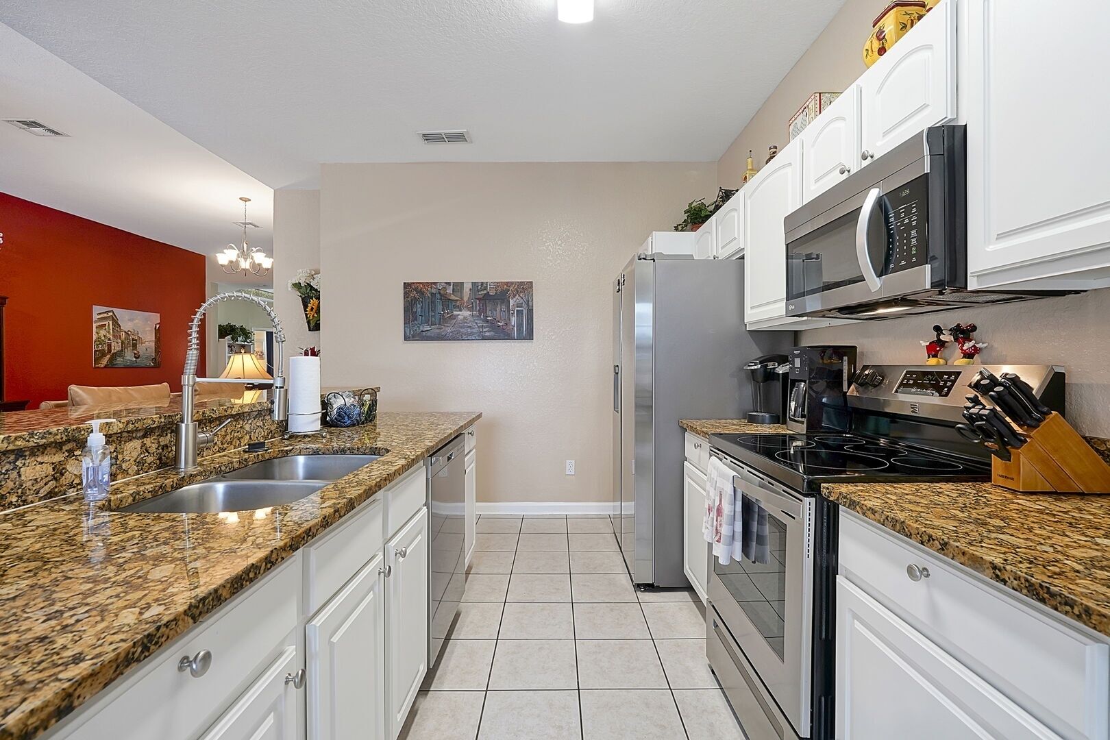 A modern kitchen with granite countertops, stainless steel appliances, and white cabinetry.