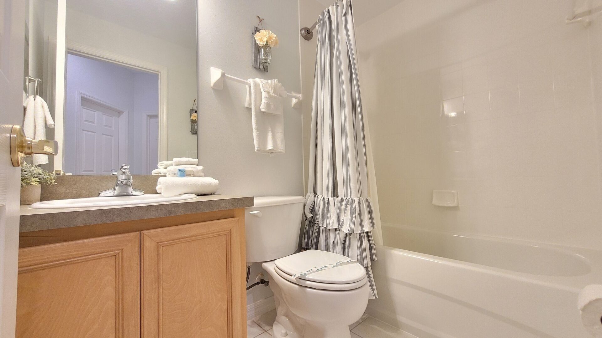 A bathroom with a white toilet, a sink with a mirror, and a shower curtain.