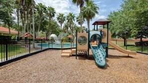 A playground with a slide, climbing structures, and a fenced pool area. - Sol826sc 4bed Solana Private Pool Home 4 Bedroom Home (Davenport)