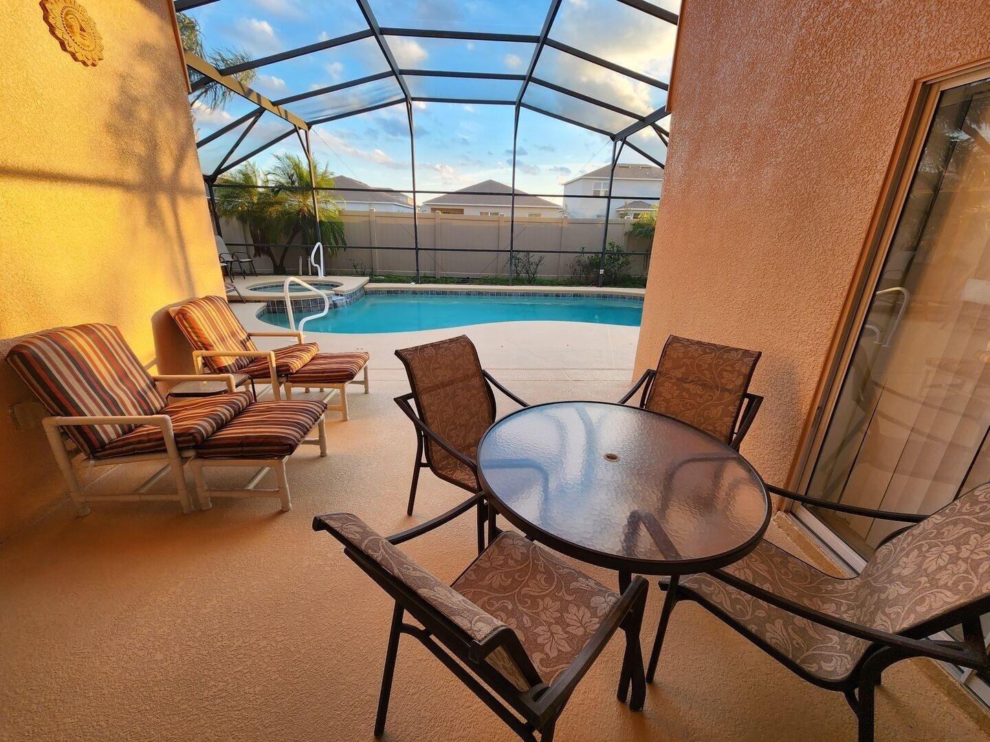 A covered outdoor area with a pool, lounge chairs, and a table.