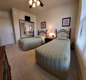 A bedroom with two beds, a ceiling fan, a mirror, and a bedside table with a lamp. - Bp122cp Mediterranean-style Condo 9 Miles To Disney World 3 Bedroom Condo (Davenport)