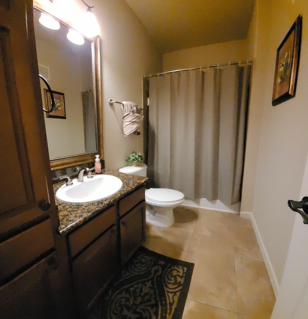 Un baño con lavamanos, espejo e inodoro.