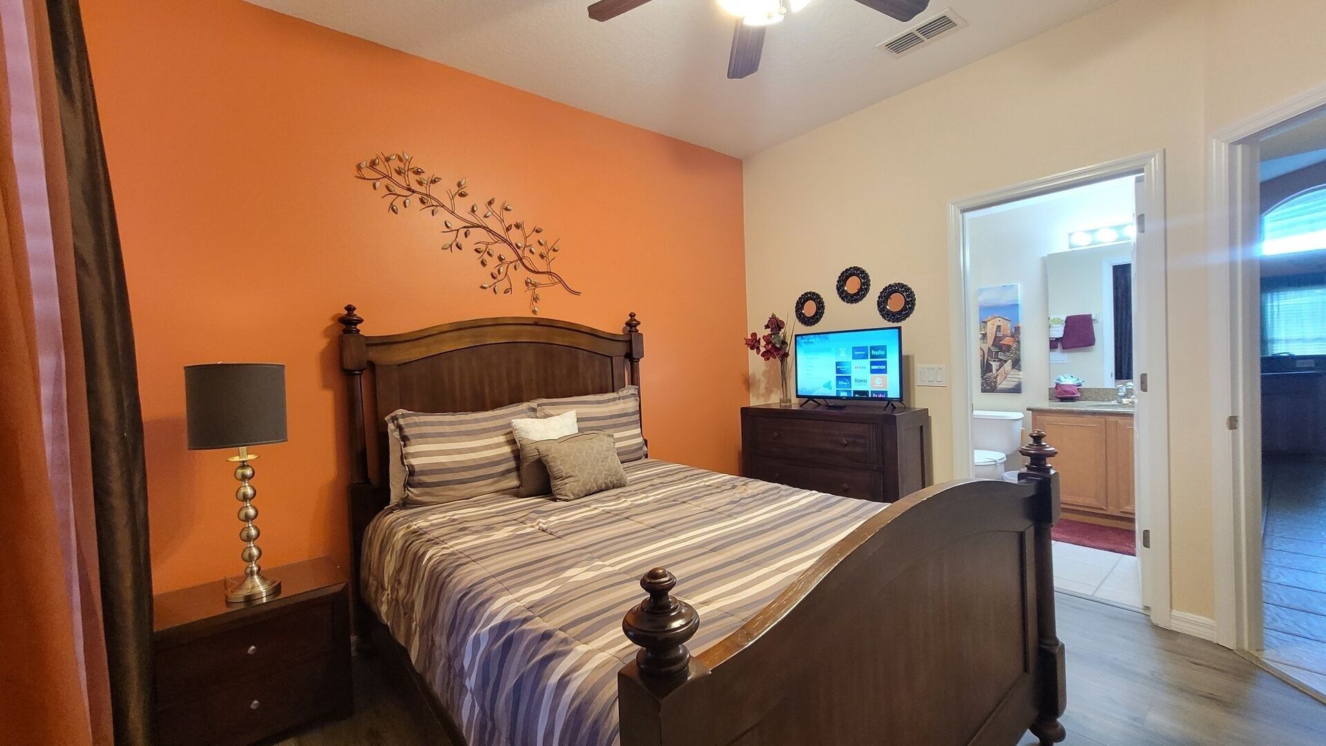 A bedroom with a bed, a nightstand, a lamp, a dresser, and a television.