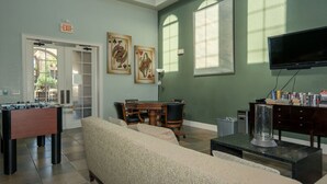 A room with a foosball table, a sofa, a TV, and a bookshelf. - Bp421cp 3 Bed Condo At Bella 3 Bedroom Condo (Davenport)