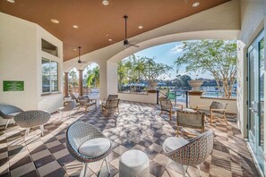 A sunlit outdoor seating area with wicker chairs and a tiled floor, overlooking a scenic view. - Av410vd Relax Retreat Villa In Aviana Resort 4 Bedroom Home (Davenport)