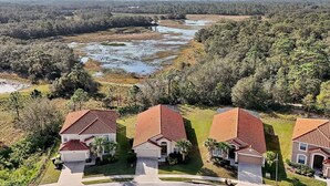 A residential area with houses featuring red-tiled roofs and white walls, surrounded by lush greenery and a river. - Av410vd Relax Retreat Villa In Aviana Resort 4 Bedroom Home (Davenport)