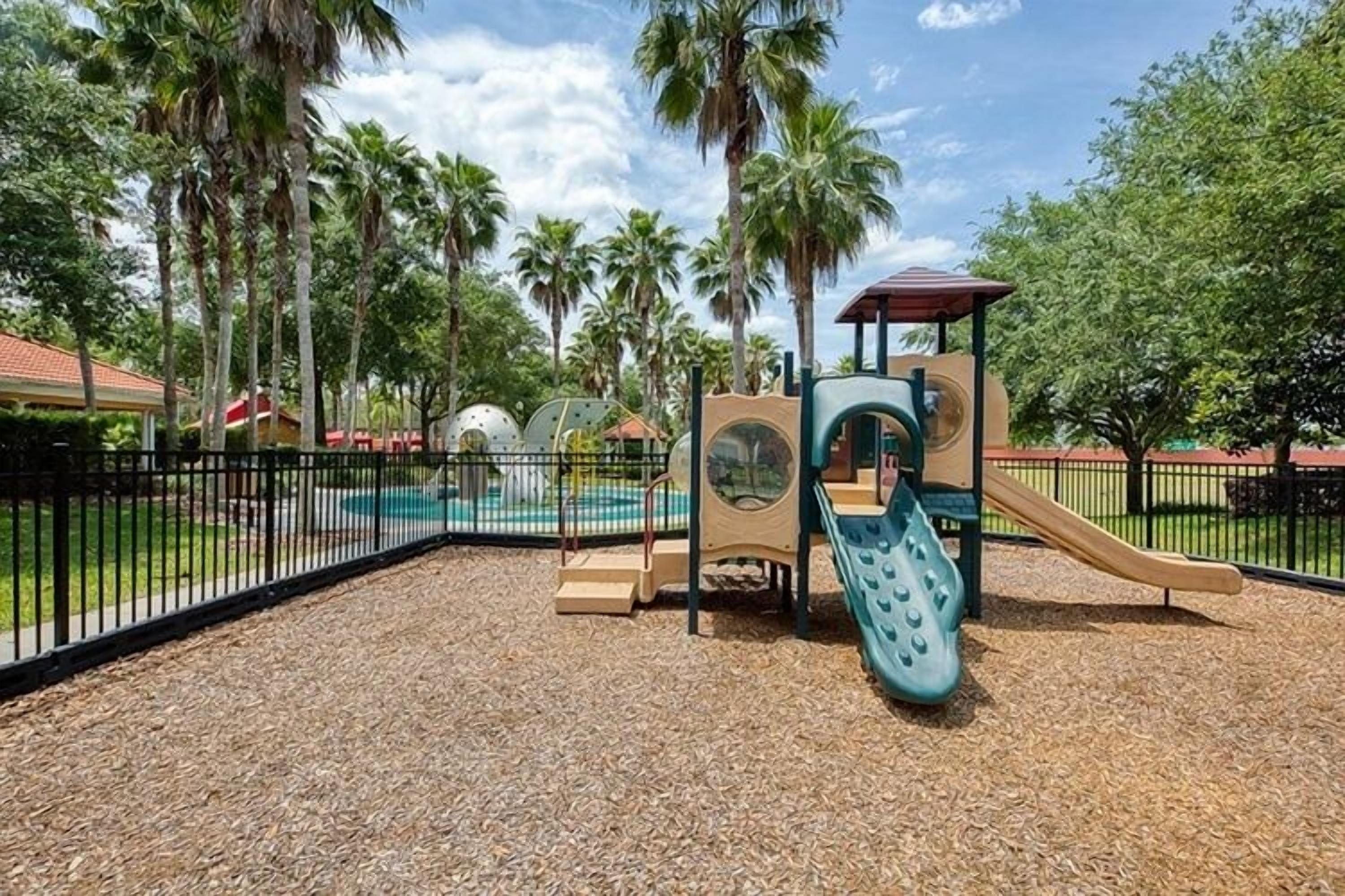 Un parque infantil con tobogán, estructuras para escalar y una zona de piscina cercada.