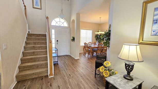 A staircase leading to a dining area with wooden flooring, a chandelier, and a table with chairs. - Cp938od 5 Bed Calabay Parc 5 Bedroom Home (Davenport)