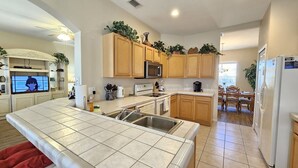 A modern kitchen with wooden cabinets, a stainless steel sink, and a built-in microwave. - Cp938od 5 Bed Calabay Parc 5 Bedroom Home (Davenport)