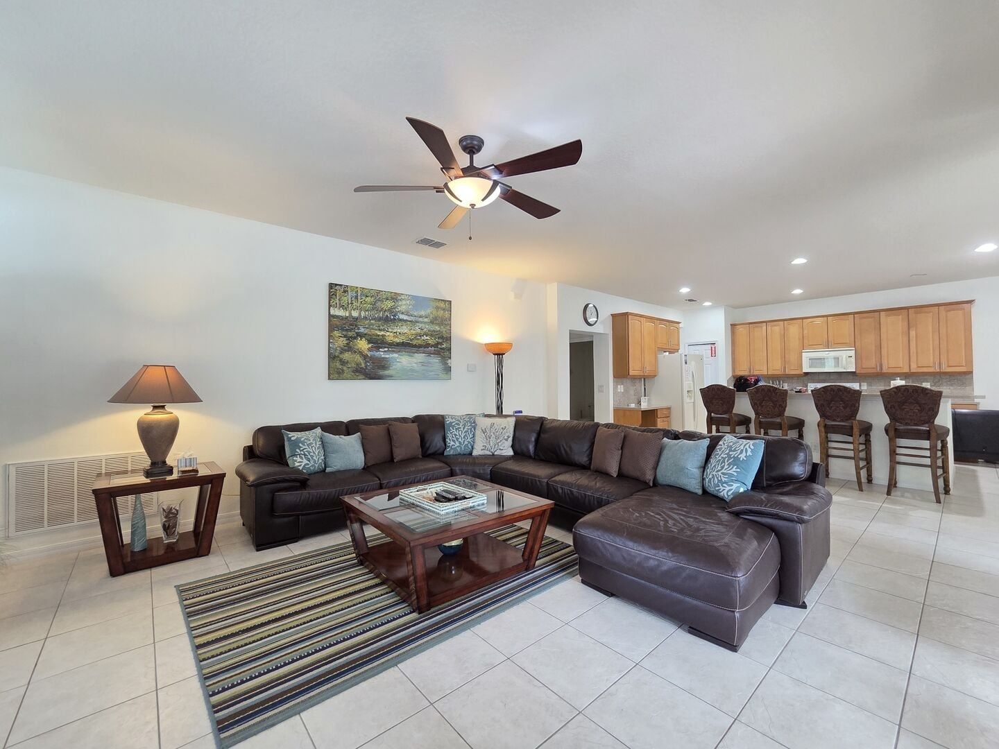 A modern living room with a sectional sofa, a coffee table, a floor lamp, and a ceiling fan.