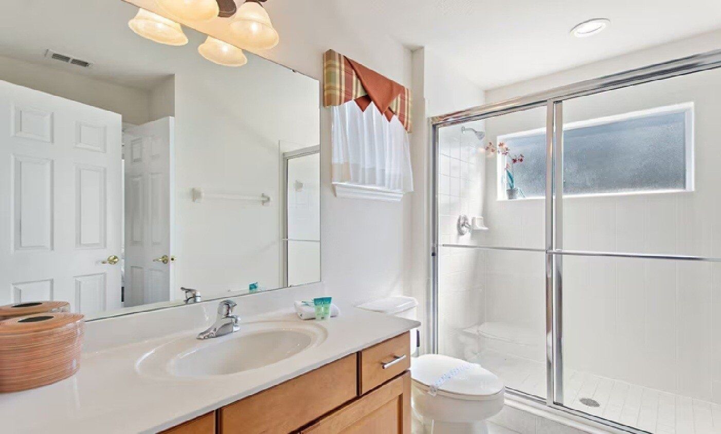 A bathroom with a large mirror, a sink, a toilet, and a glass shower enclosure.