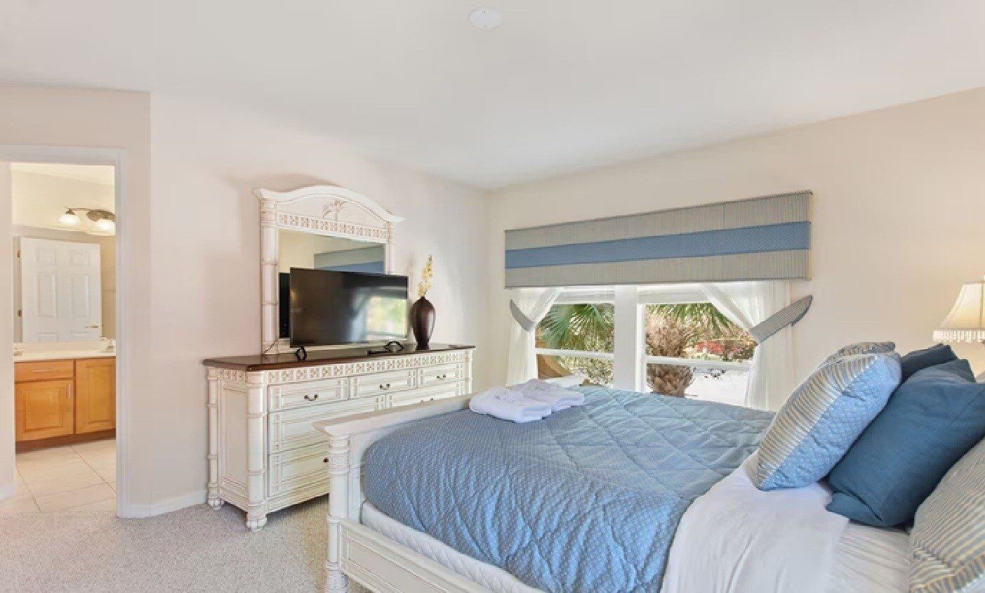 Un dormitorio con una cama grande, un aparador, un televisor y una ventana con vistas.