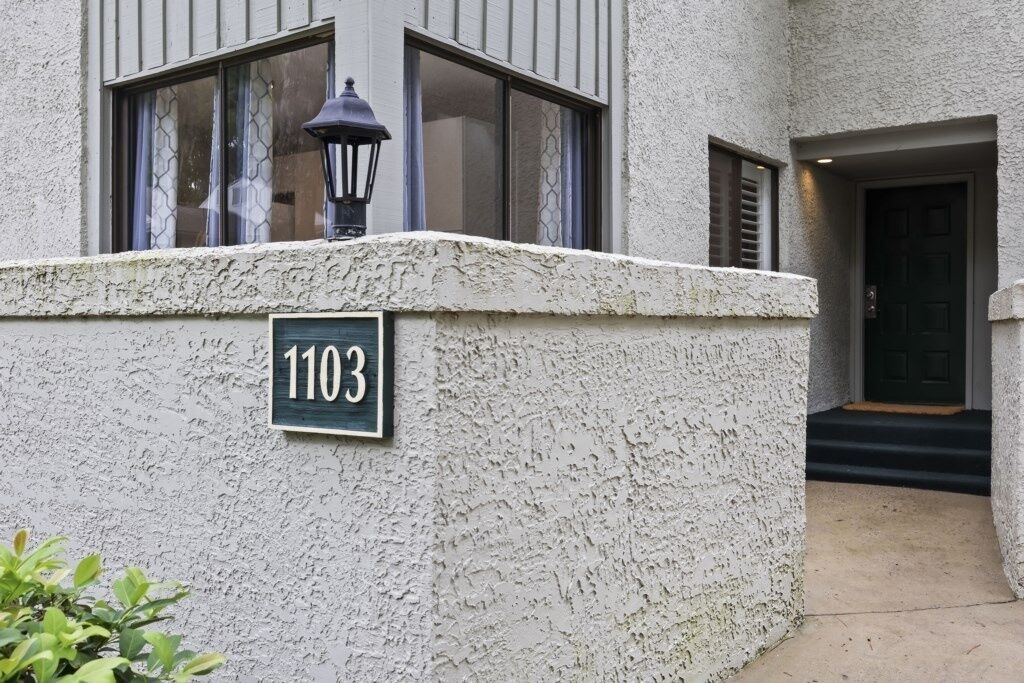 A building with a textured facade and a number sign '1103' on the wall.
