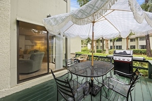 An outdoor patio with a round metal table and chairs, a grill, and a covered seating area with white umbrellas. - Harbour Master - Monthly Rates Through 2/28/26! 3 Bedroom Villa (Hilton Head Island)